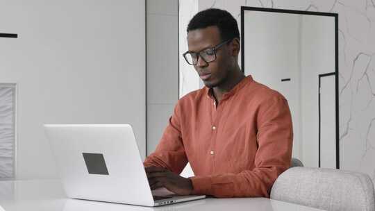 男子坐在桌子前用笔记本电脑工作视频素材模板下载
