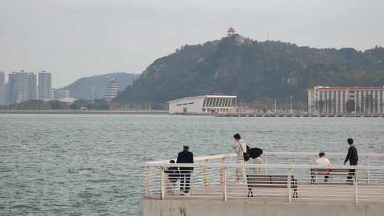 几位游客在海边亲水平台游览打卡拍照