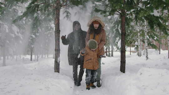 年轻的多样化家庭在冬季森林中享受雪雨