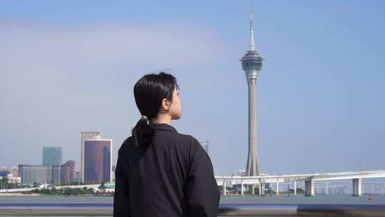 游客站在海岸边看澳门城市风景观望澳门塔