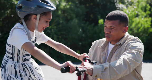 家庭，父亲和女儿与自行车教学骑在街上，户