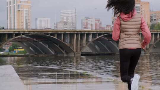 一个女人在河岸的人行道上奔跑