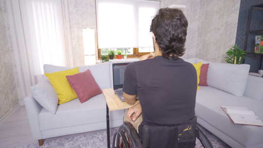残疾的年轻人坐在轮椅上，用笔记本电脑工作