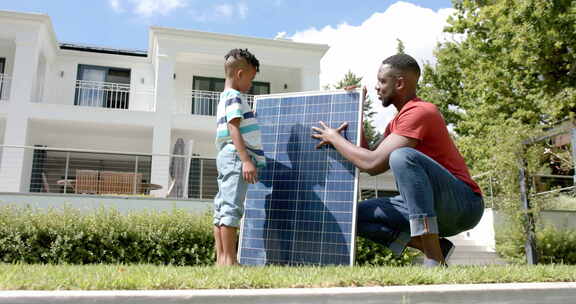 非裔美国父子在家户外检查太阳能电池板