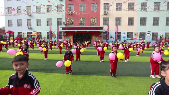 幼儿园小朋友操场上拿着气球跳舞