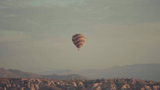 一个热气球飞过沙漠山丘和山脉