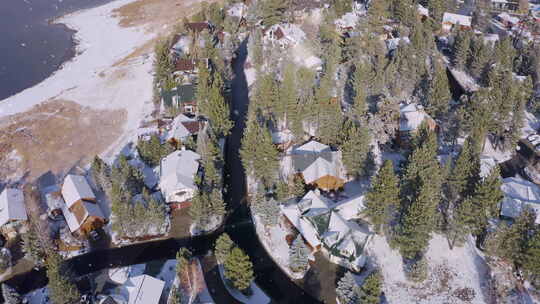 雪花落在小屋的屋顶上，有着茂盛常绿松木的小村庄