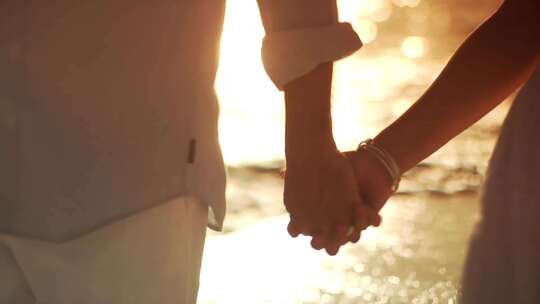 海边手牵手的情侣、新婚夫妇手牵手走在海边