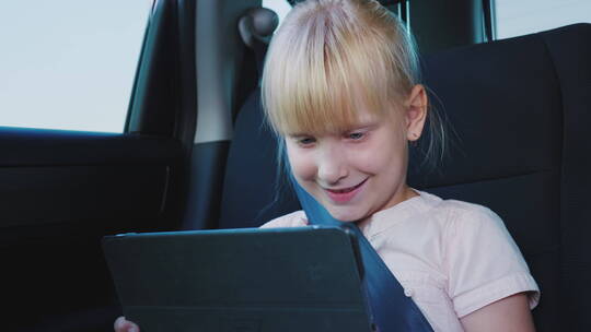 在汽车里玩平板电脑的女孩