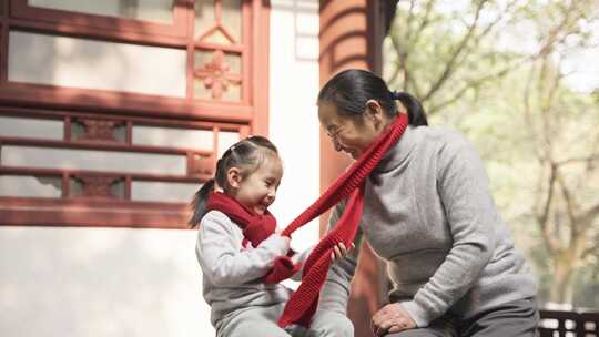 新年春暖阳光里小女孩孙女给奶奶戴红围巾