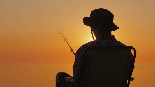 男人坐在海边钓鱼的后视图