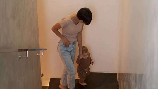 母亲牵婴儿在家中楼梯学步