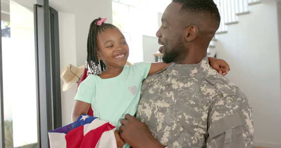 穿着军装的非裔美国人父亲在家抱着一个梳着