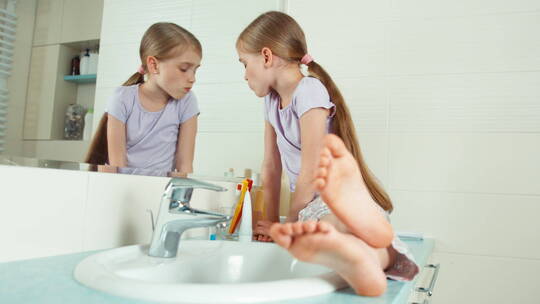 小女孩坐在水池上对着镜子刷牙