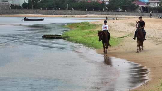 航拍威海市环翠区金海路沙滩上的骑马人