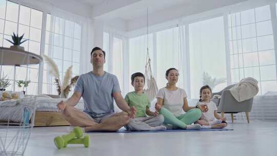 友好的家庭与孩子在家里练习瑜伽