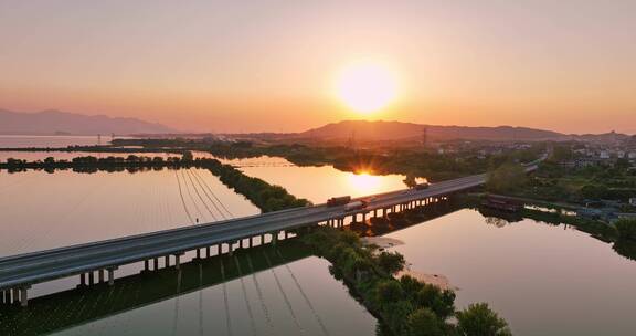 航拍夕阳下穿过鄱阳湖的乡间高速公路