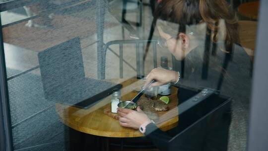 女人坐在咖啡厅窗边吃饭