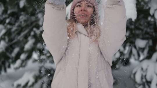 中年女人对着镜头吹雪花微笑着穿着白色冬季