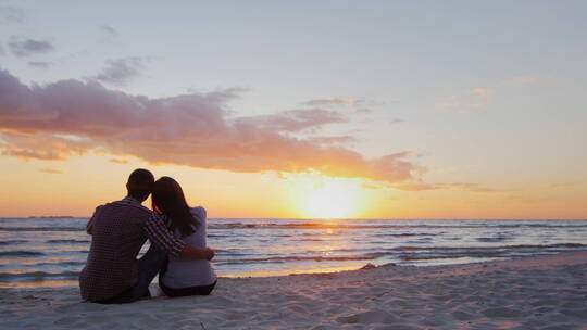 夫妇坐在沙滩上欣赏海上日落视频素材模板下载