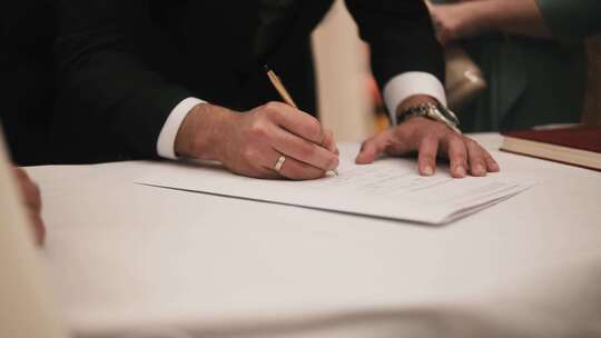 新郎在市政厅签署结婚文件，特写。