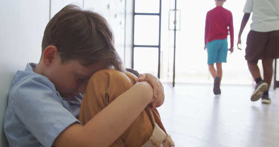 悲伤的高加索男孩坐在学校走廊上，用手捂住头的视频