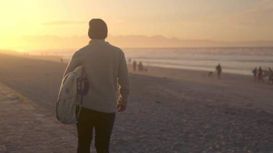 夕阳黄昏男人拿着冲浪板