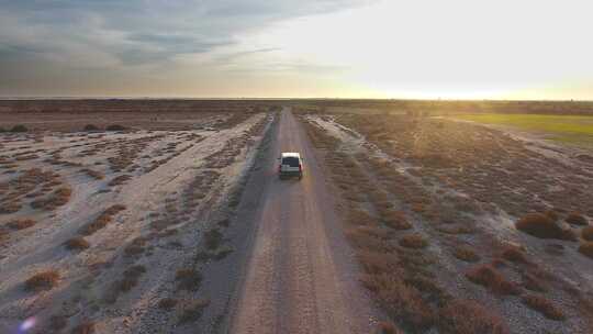 日落时，汽车在平坦地形上的泥土路上行驶。终点和终点