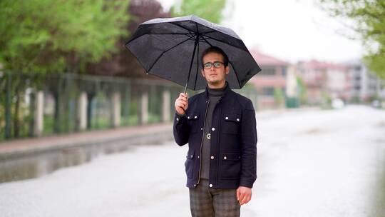 年轻人在雨天撑着雨伞