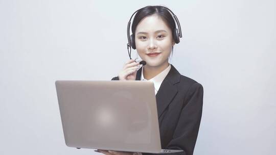 一位西装女性客服 在笔记本电脑前拨打电话