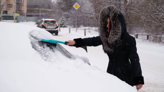 女人在冬天打扫车上的雪