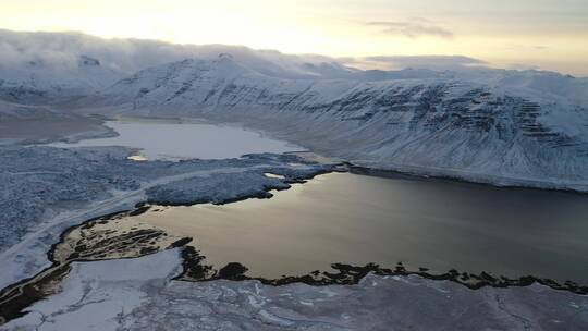 航拍冰岛白雪覆盖的山脉环绕着一个湖