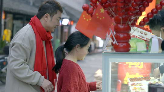 街头父女俩驻足观看糖葫芦摊位