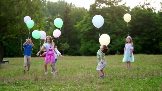 草地上一群孩子手拿气球玩耍