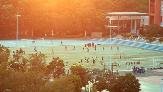 夕阳下学校足球场上踢球的儿童们