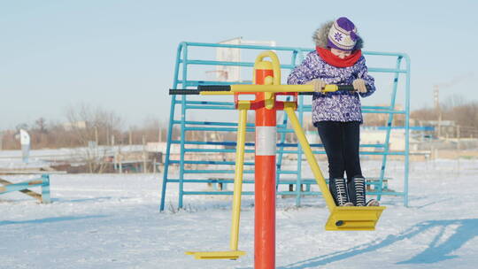 冬季女孩在公园里玩秋千