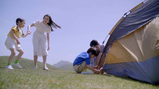 快乐的一家四口在郊区搭帐篷视频素材模板下载