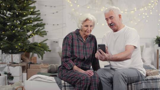 老年夫妇坐在沙发上一起自拍视频素材模板下载