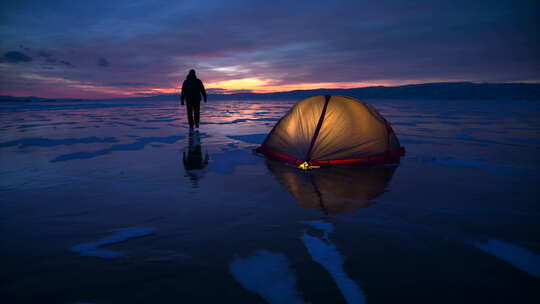徒步旅行者从冰冻湖暮光之城冰面上的发光帐