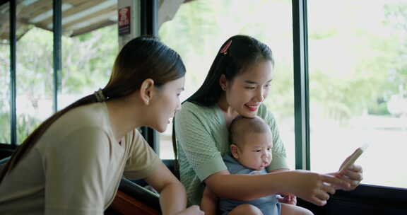 两个年轻的亚洲女人在咖啡馆里开心地和一个