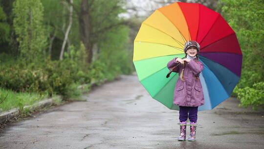 女孩在公园小路上转动彩虹雨伞