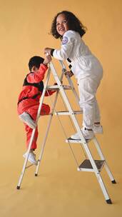 两个穿着宇航服的孩子正在爬梯子竖屏