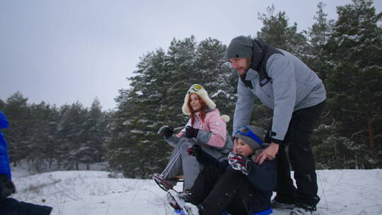 父母带着孩子在森林里滑雪橇视频素材模板下载