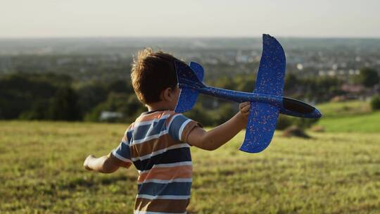 男孩拿飞机模型奔跑在草地上视频素材模板下载