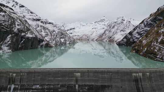 令人惊叹的无人机镜头在阿尔卑斯湖、水坝和被崎岖的穆包围的巨大阿尔卑斯水库上空