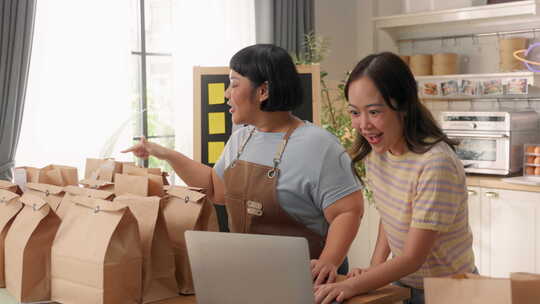 亚洲女性兴奋地对厨房笔记本电脑上的好消息