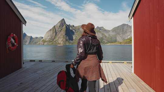 一个年轻的旅行者女人走在木制码头上