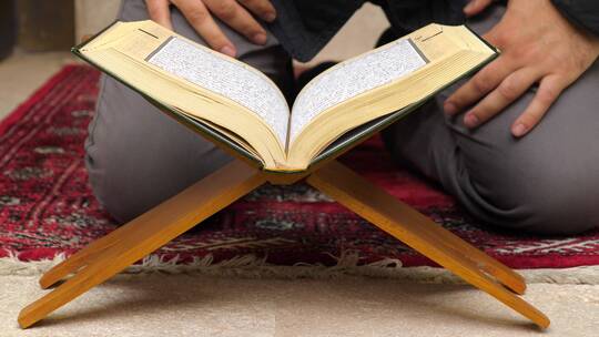 一个人在祈祷室前读古兰经的镜头