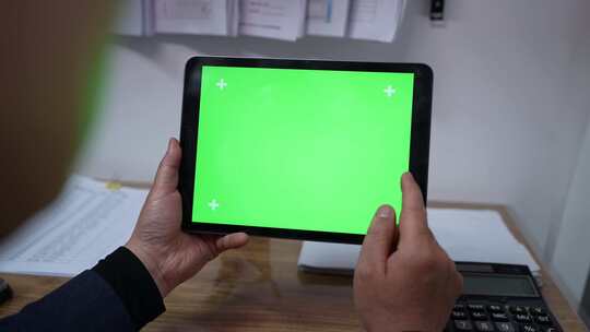 男子操作绿色屏幕的iPad