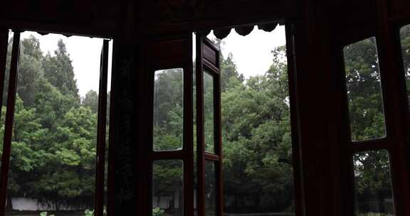 古建窗边观雨中绿树景色